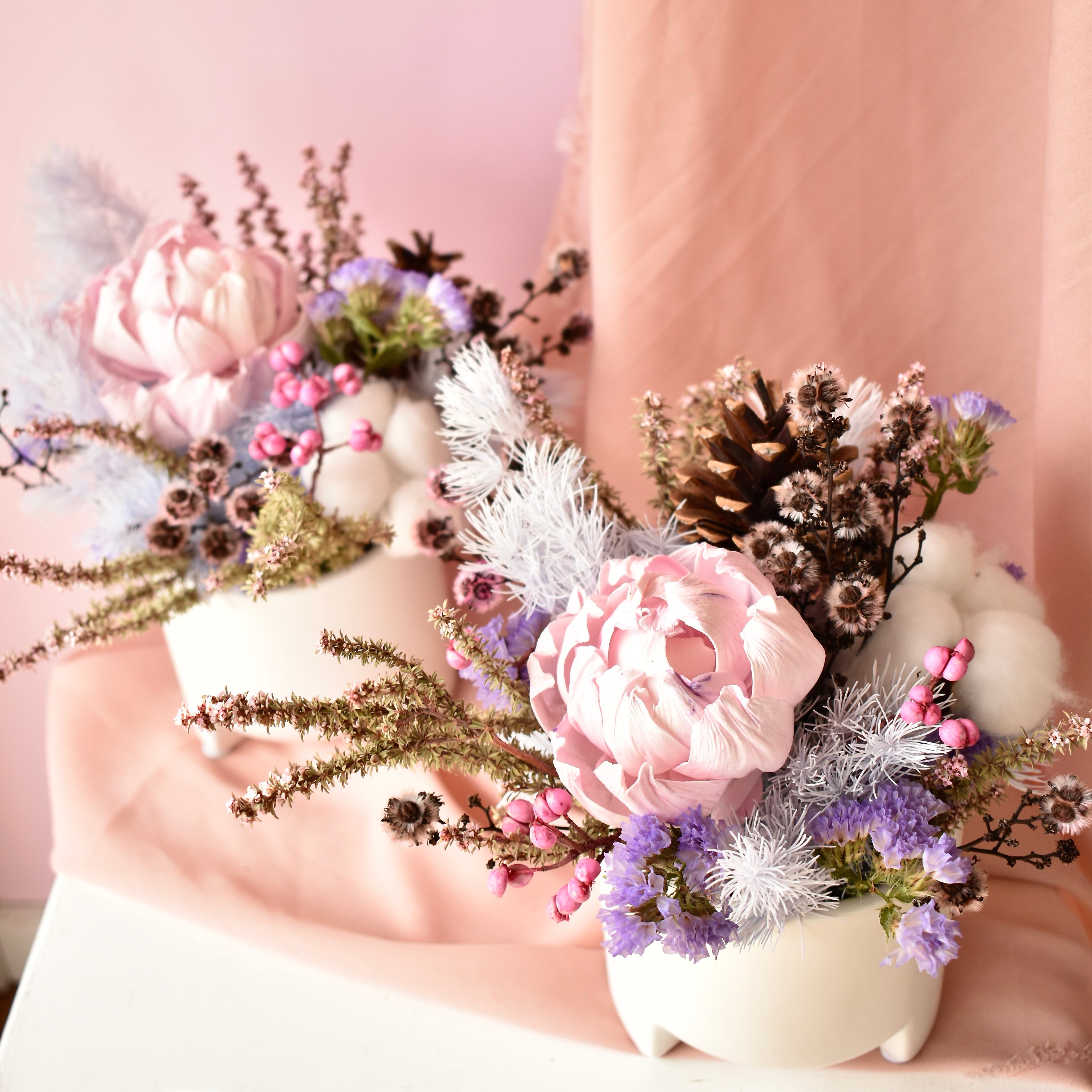 Two small dried flower arrangements. Created in shades of mauve, pink white and brown.