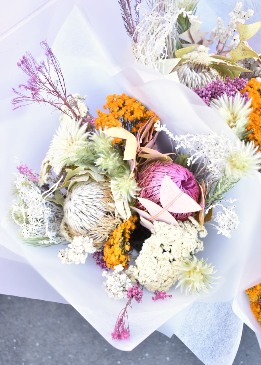 Bundles of dried flowers. Colours of pink, white, silver and mustard. Made with erica, banksia and Australian native flowers. Wrapped in white florists paper.