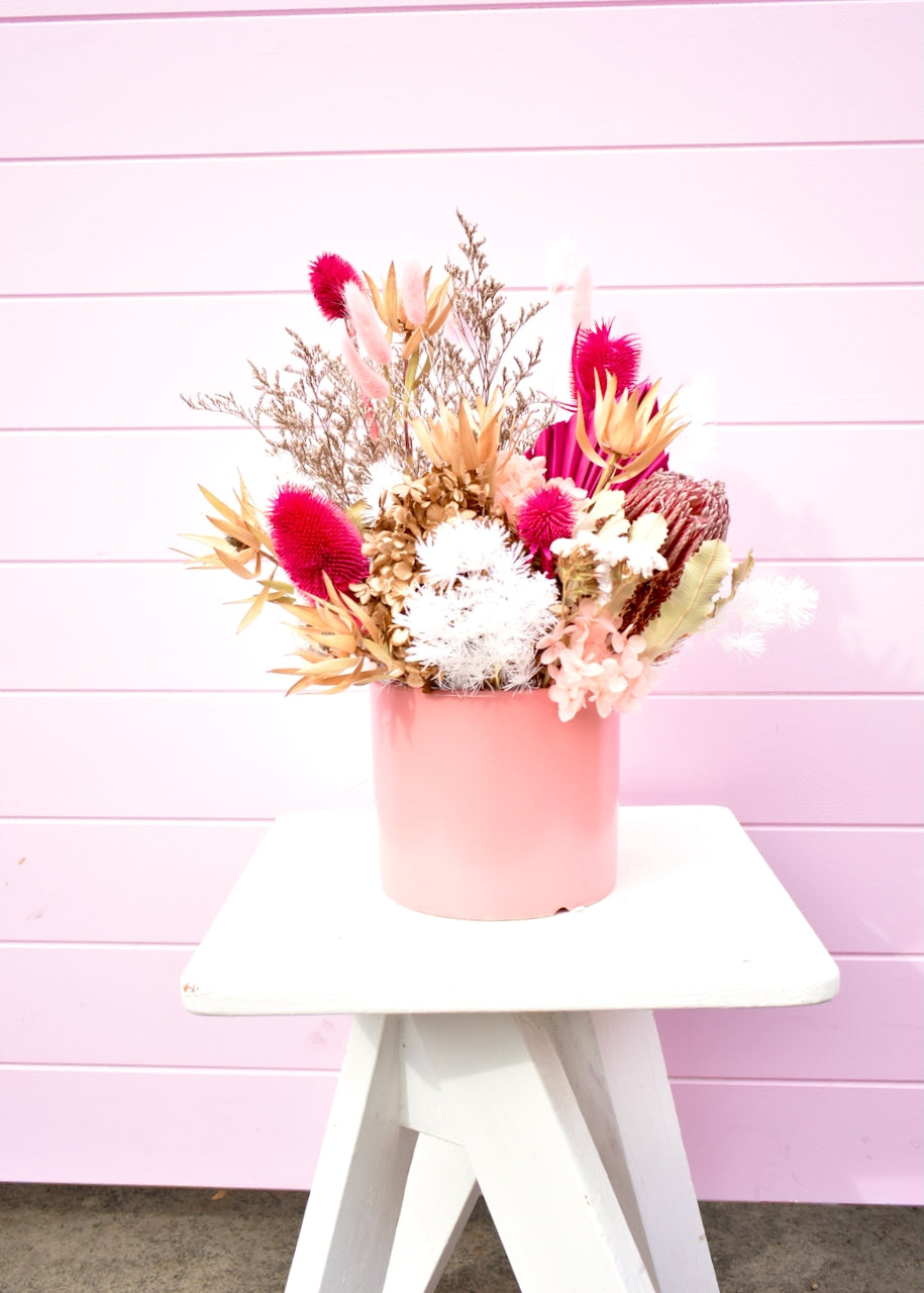 Dried flowers in pink, white and cream. Banksia and fern with hot pink palm in a coral pink pot