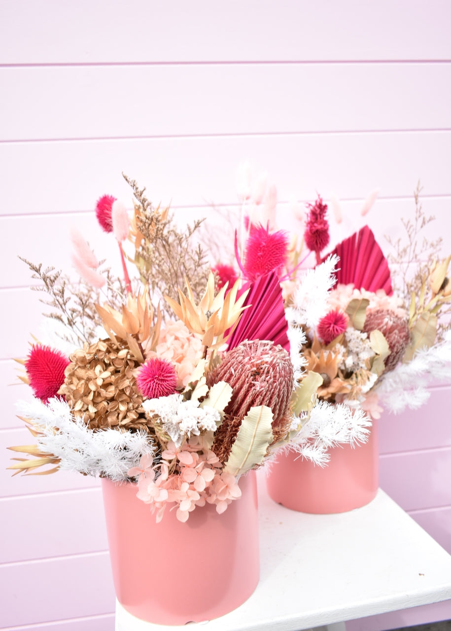 Dried flowers in pink, white and cream. Banksia and fern with hot pink palm in a coral coloured pot