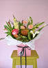 Bouquet of flowers in a pink box on a green stool with a pink background