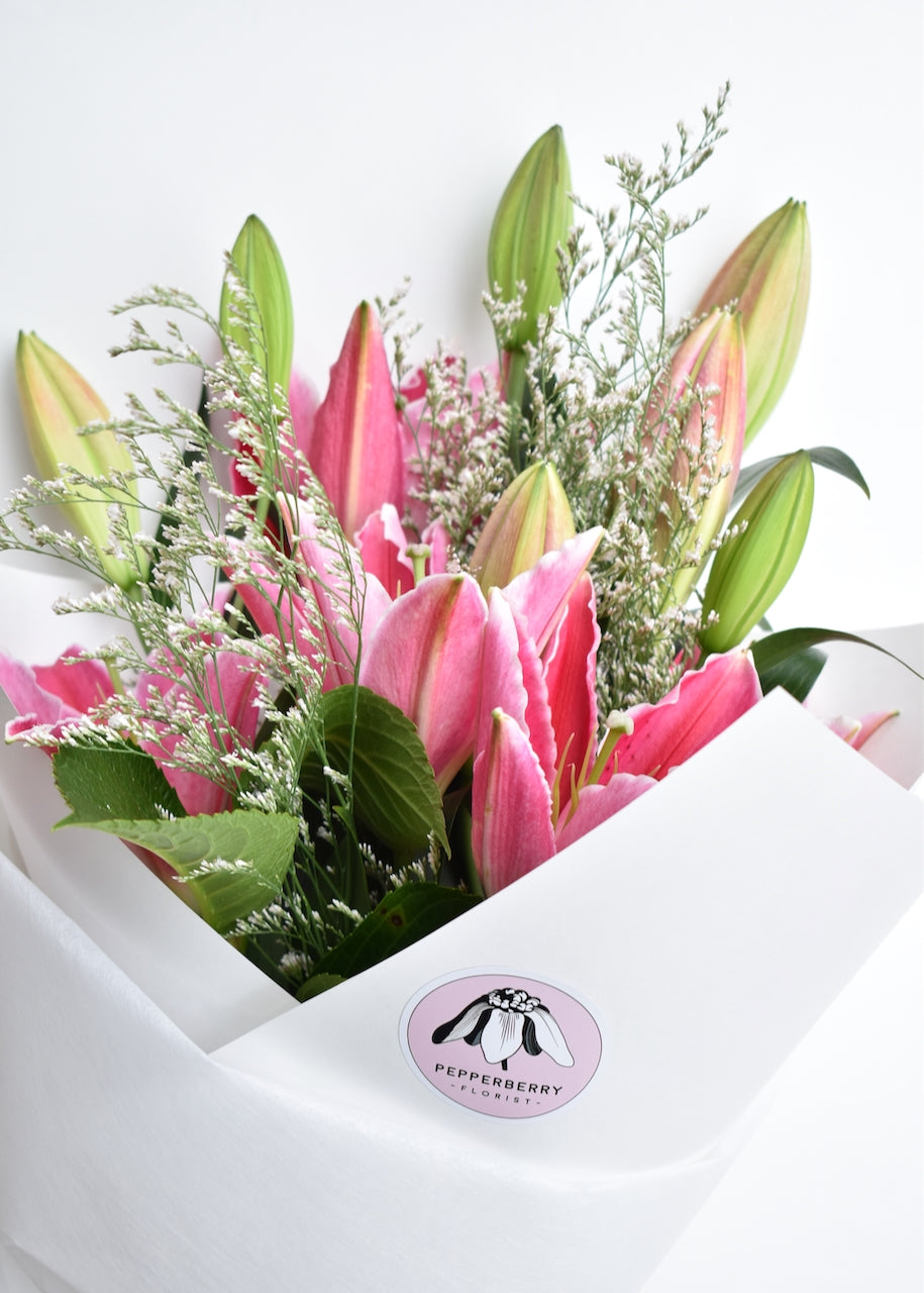 Bouquet of pink lilies in a white paper giftwrap
