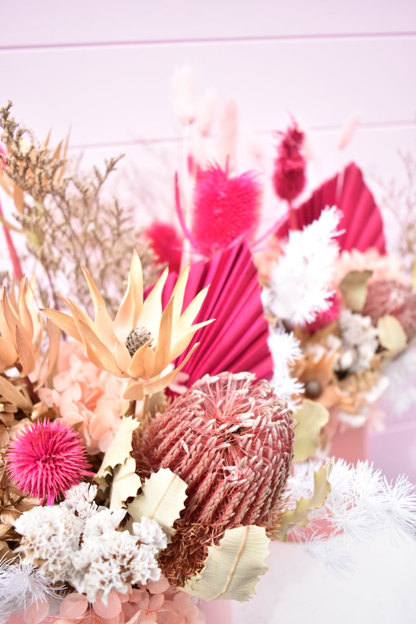 Dried flowers in pink, white and cream. Banksia and fern with hot pink palm