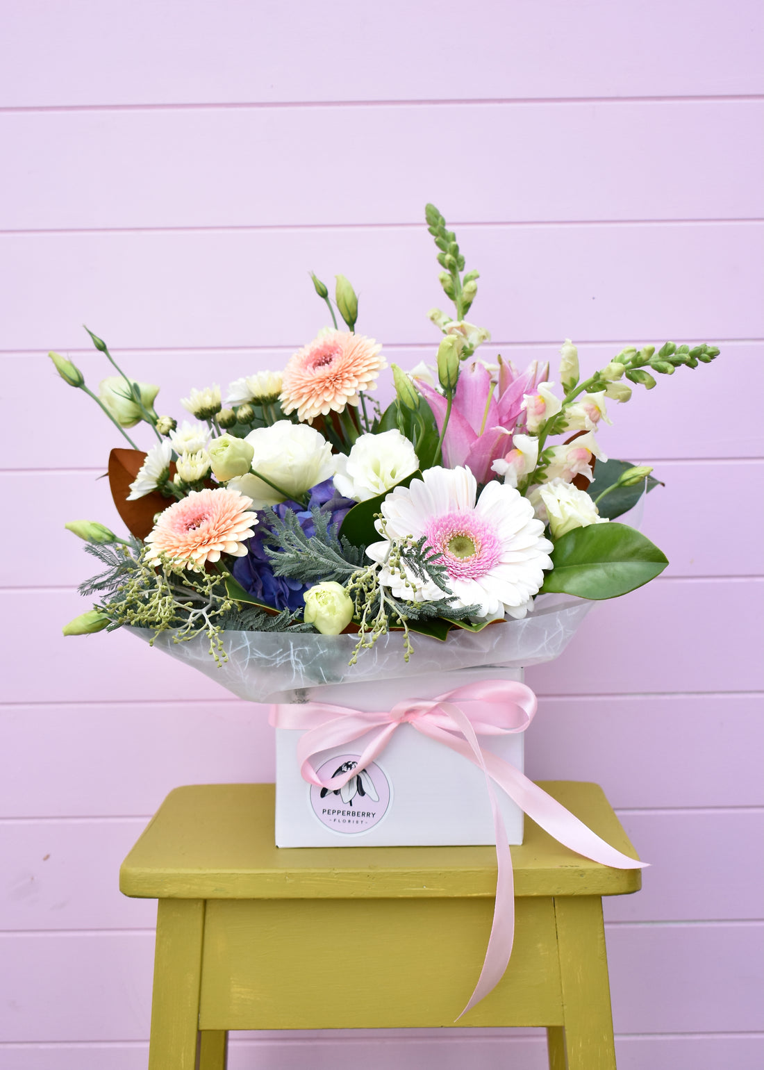 Pastel coloured fresh flowers in a white box. Roses, daisies, lillies in white, pink, peach