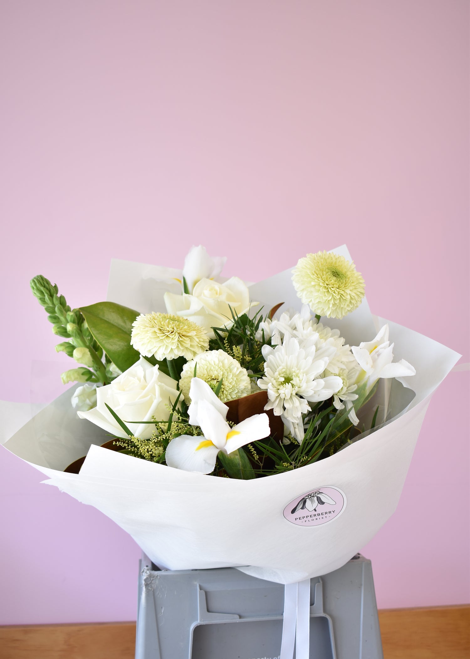 Bouquet of flowers wrapped in white paper against a pink background