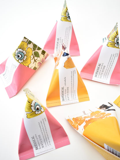 Pink &amp; yellow floral triangular packages containing botanical bath bombs