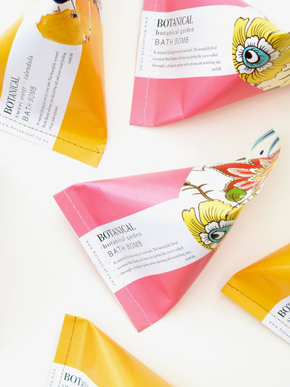 Pink &amp; yellow triangular packages containing botanical bath bombs