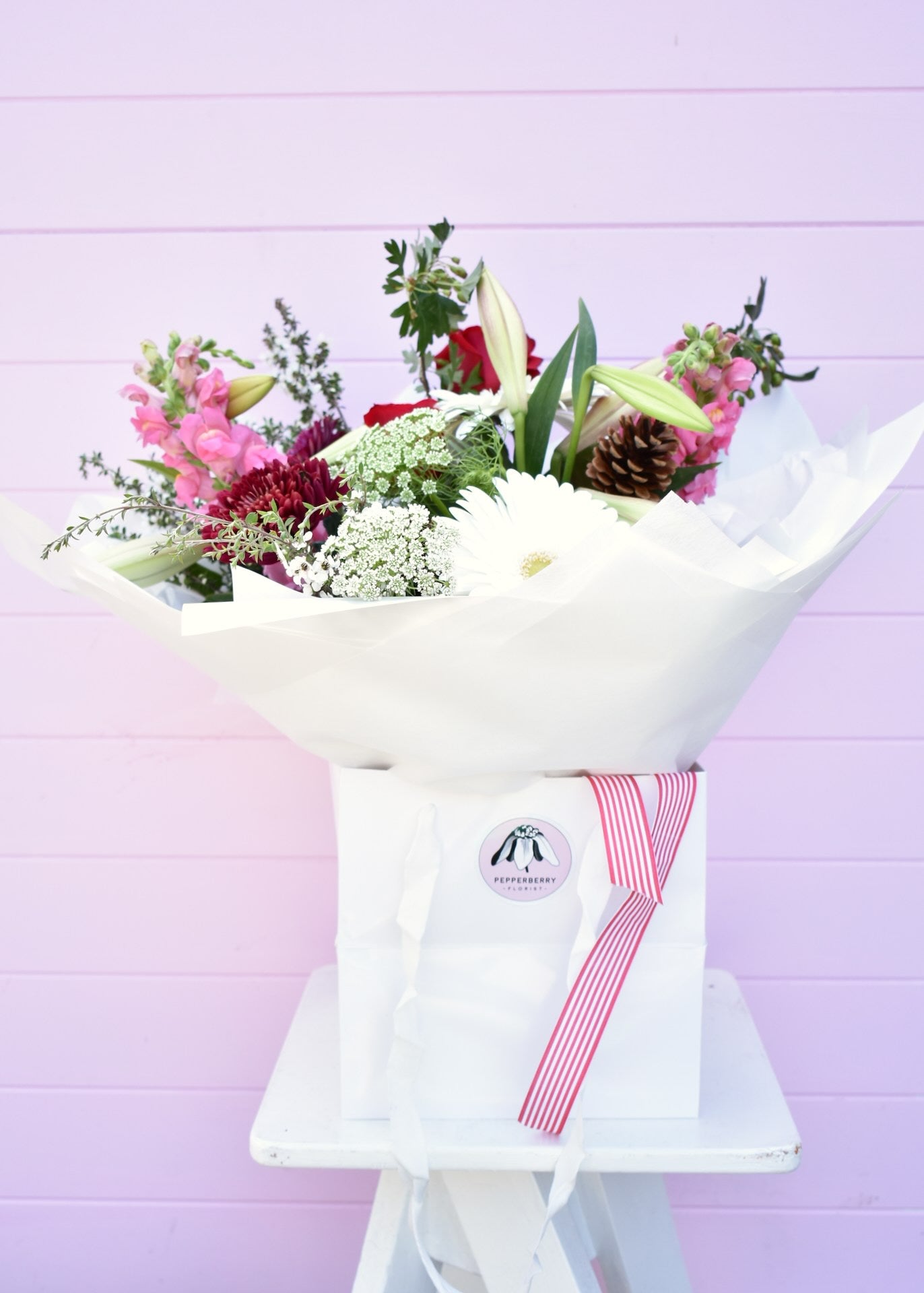 Christmas style bouquet of fresh flowers in a white paper wrap and bouquet bag. Red, white, pink and green flowers