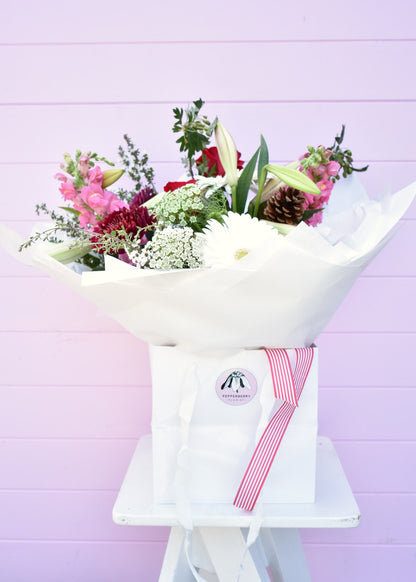 Christmas style bouquet of fresh flowers in a white paper wrap and bouquet bag. Red, white, pink and green flowers