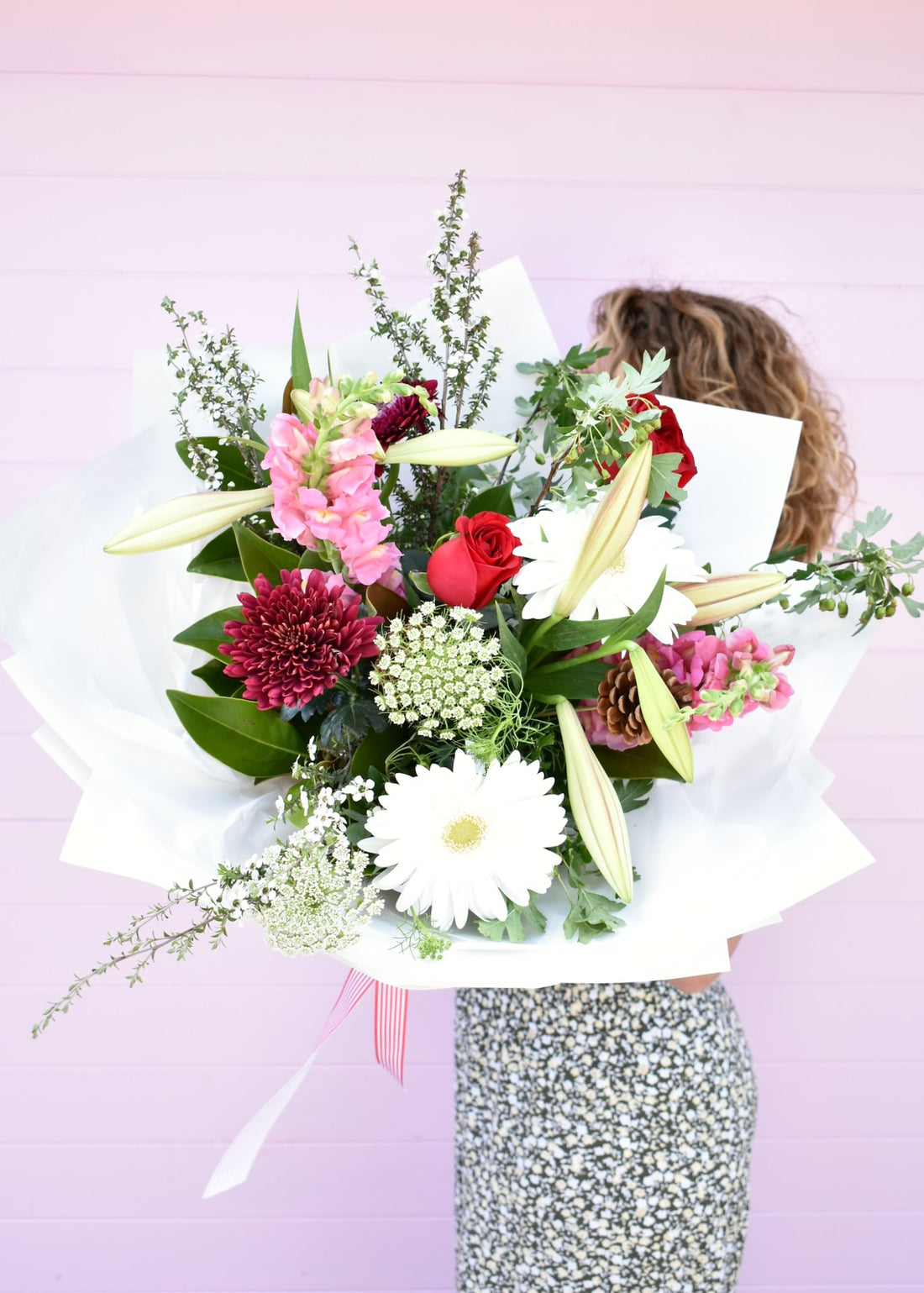 Florist holding a bouquet of fresh flowers in a festive Christmas style. Red, white, pink and green