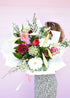 Florist holding a bouquet of fresh flowers in a festive Christmas style. Red, white, pink and green