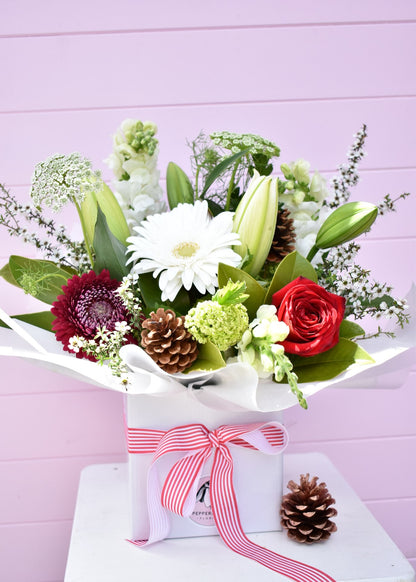 Christmas style flowers arranged into a white box. Colours of red, white and green fresh flowers