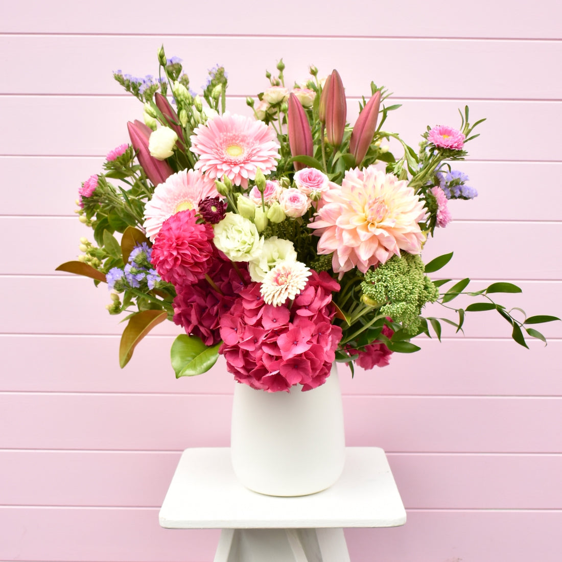 A white table holding a large pink and white flower arranagement
