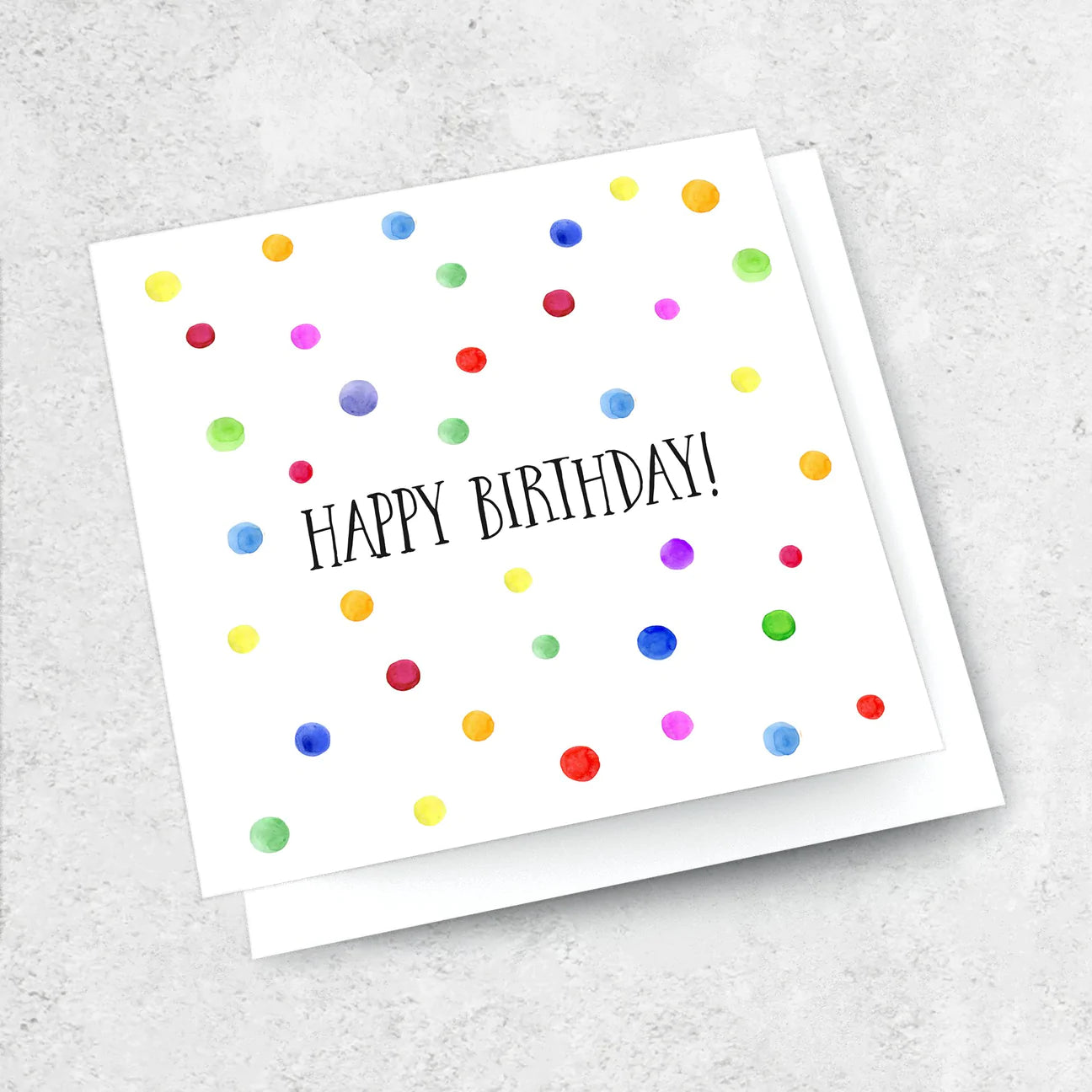 A White greeting card with colourful spots and text reading &quot;Happy Birthday&quot;.