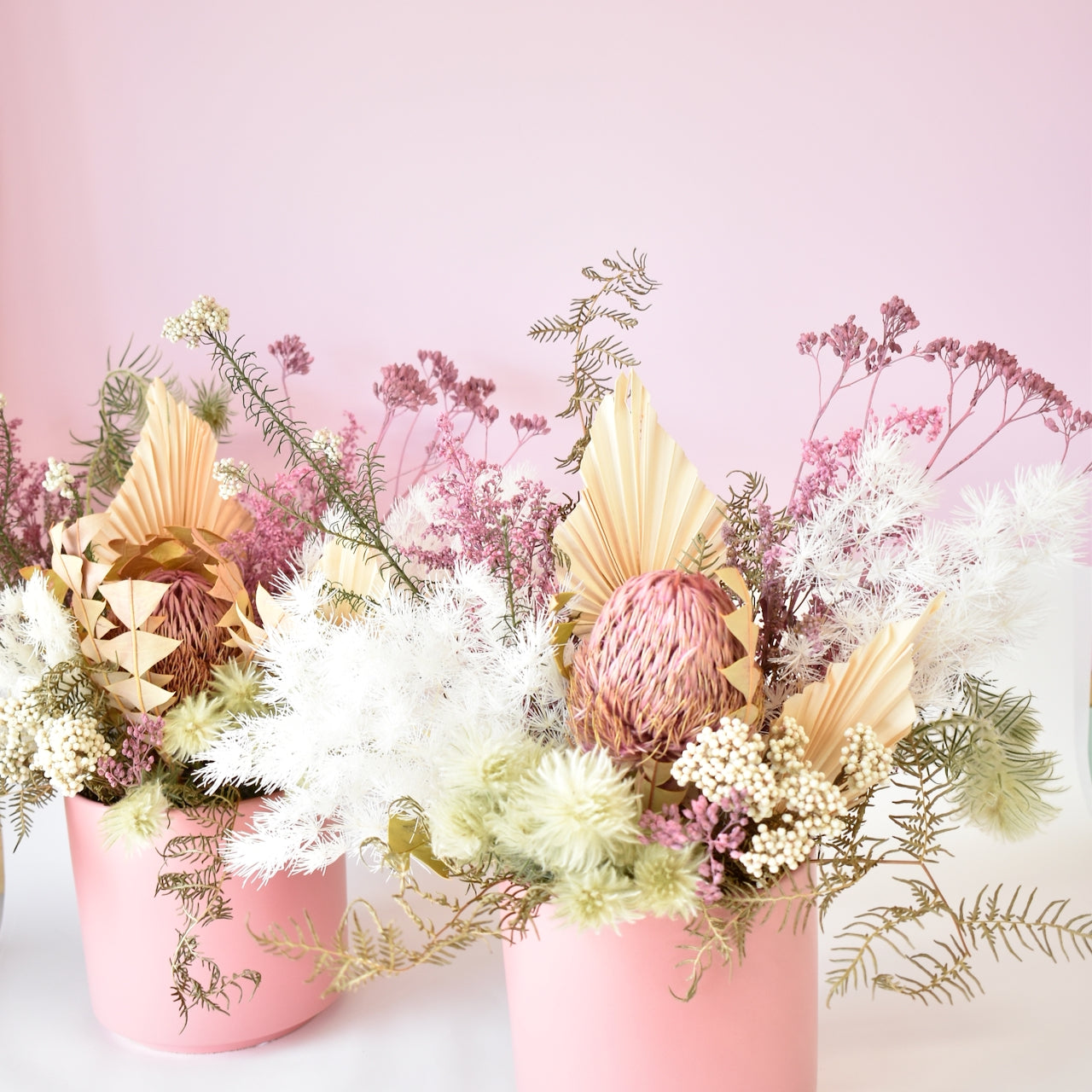 Lovely dried flower arrangement. White ferns, pink banksia, peach palm leaves with white rice flower in pink pot