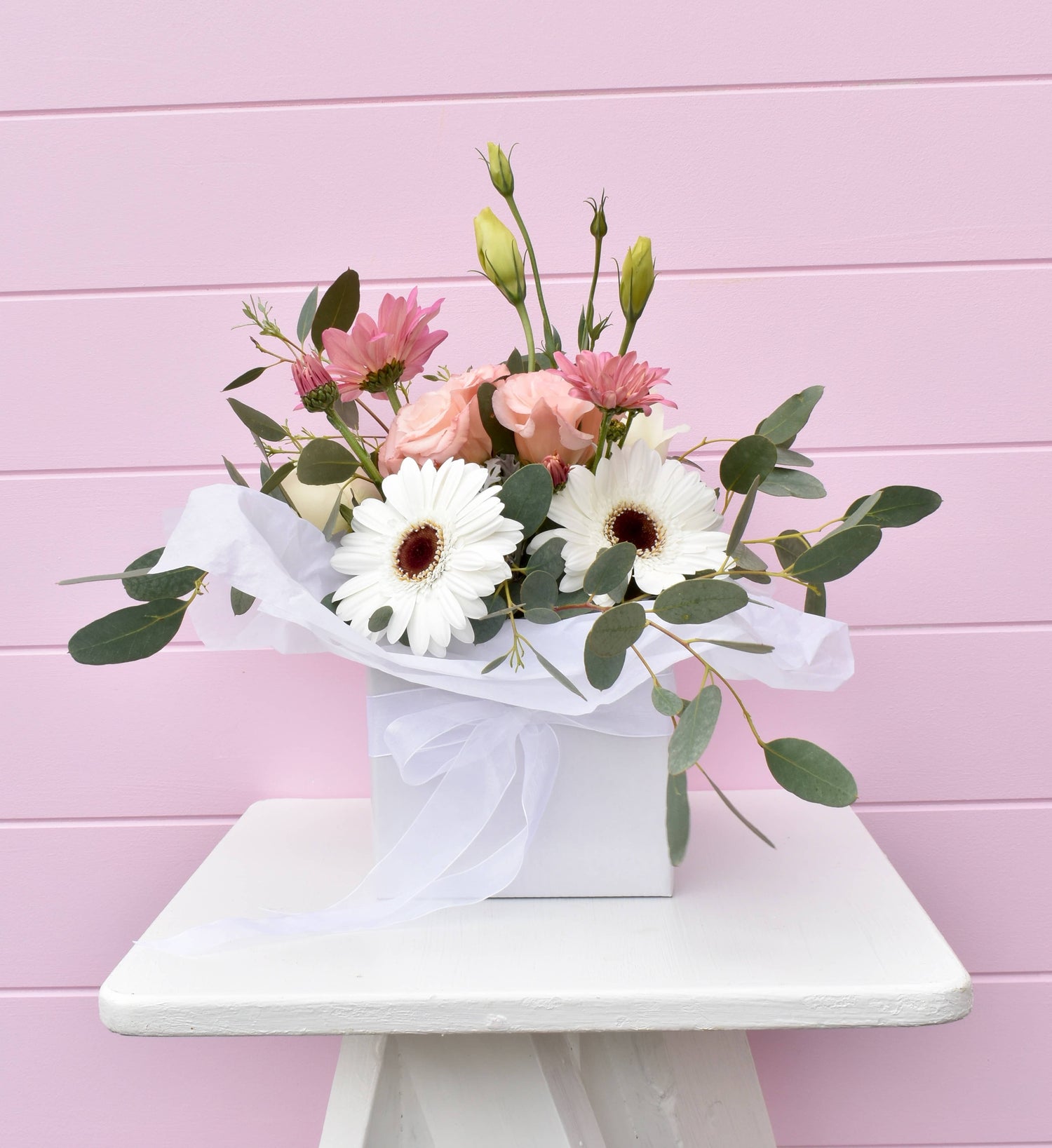 A white box containing a flower posy in white and pink