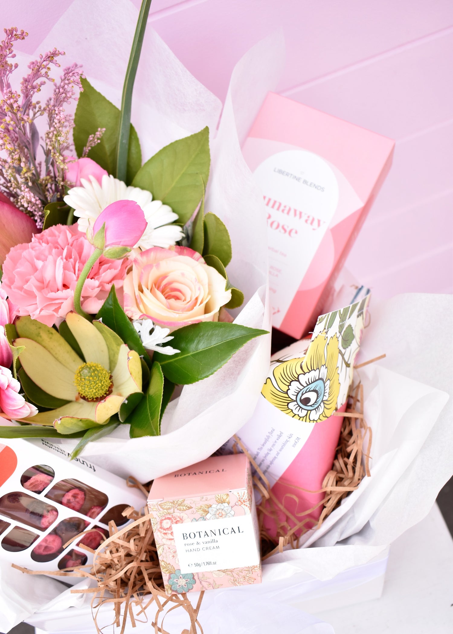 Gift hamper created by florist. Pretty pink fresh flowers, chocolate, bath bom, hand cream and box of rose tea